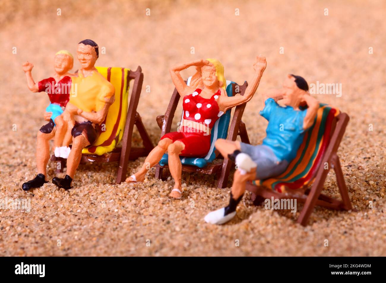 Konzeptionelles Bild einer Miniaturfigur, Leute saßen auf Liegestühlen an einem Sandstrand, Urlaubskonzept Stockfoto