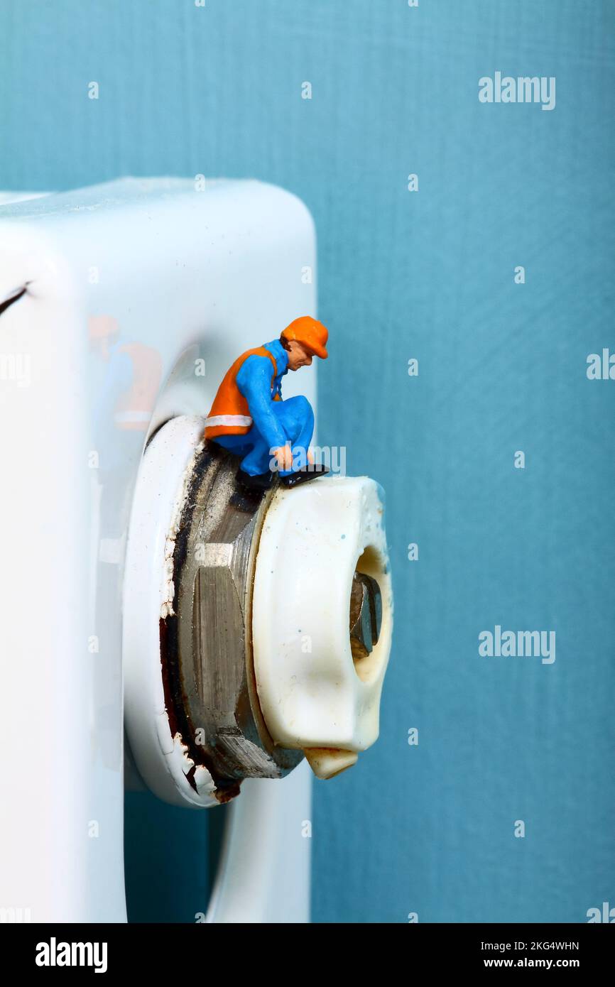 Miniaturfigur, Arbeiter, der ein Kühlerentlüftungsventil inspiziert, Konzept mit energiesparenden Spitzen Stockfoto