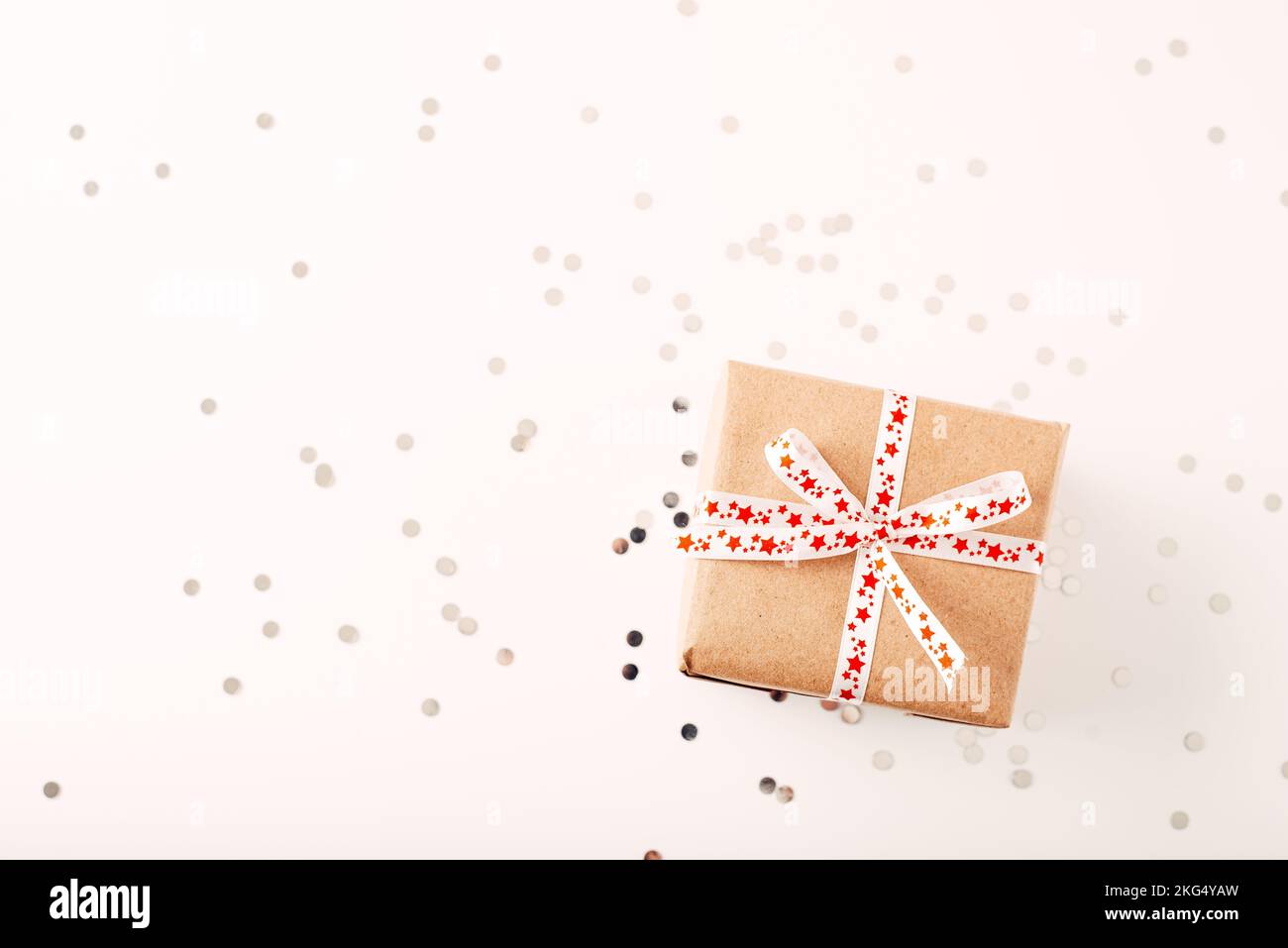 Weihnachtsgeschenk oder Geschenk und Konfetti auf weißem Tisch. Grußkarte mit Weihnachtsdekoration. Stockfoto