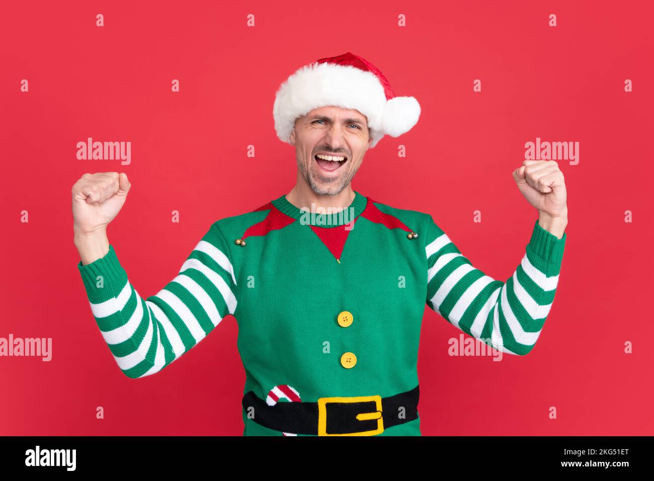 Spüren Sie den Erfolg. Fröhlicher schreiender Mann in Elfenkostüm. der weihnachtsmann mit dem weihnachtsmann-Hut Stockfoto