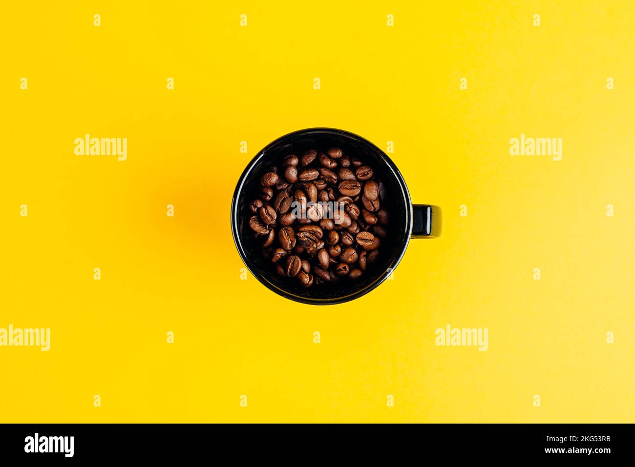 Kaffeebohnen in einer schwarzen Tasse auf gelbem Hintergrund Stockfoto