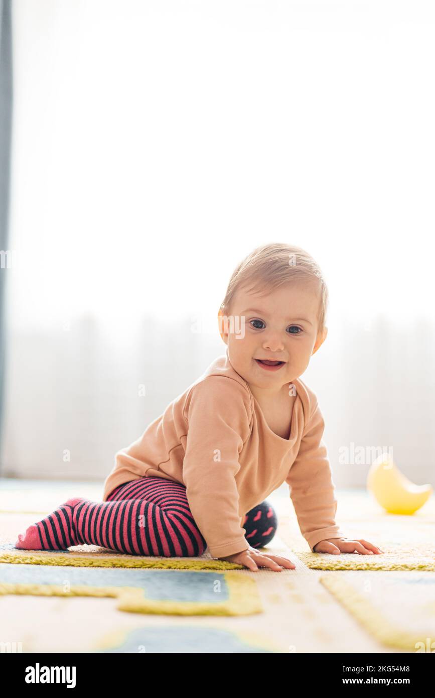 Ein Kind von 7 Monaten krabbelt auf dem Teppich im Kinderzimmer Stockfoto