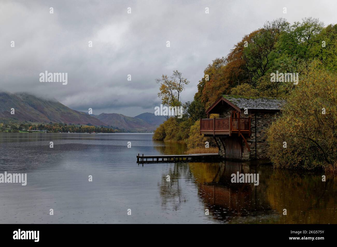 Ein paar Regentropfen verderben diesen Blick auf Ullswater in den englischen Seen nicht, da das Bootshaus des Herzogs von Portland aus den Bäumen emporsteigt Stockfoto