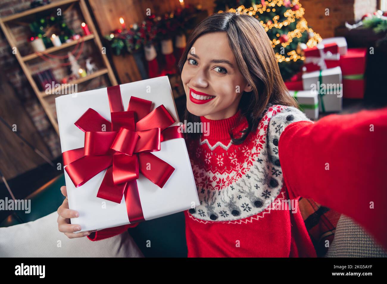 Selfie Porträtfoto von fröhlichem fröhlichem Mädchen, das sie mit dem neuen weihnachtsmann erschießt weihnachtsbaum hinter dem weihnachtsmann trägt einen hässlichen roten Pullover drinnen Stockfoto