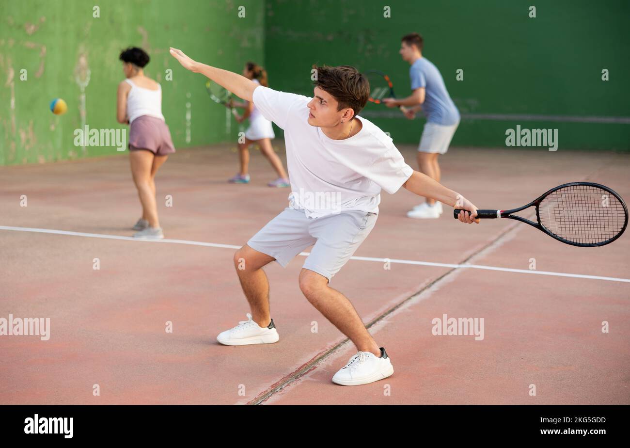 Männlicher Sportler, der sich mit Schläger auf den Ball vorbereitet. Frontenis-Spiel auf dem Platz im Freien Stockfoto