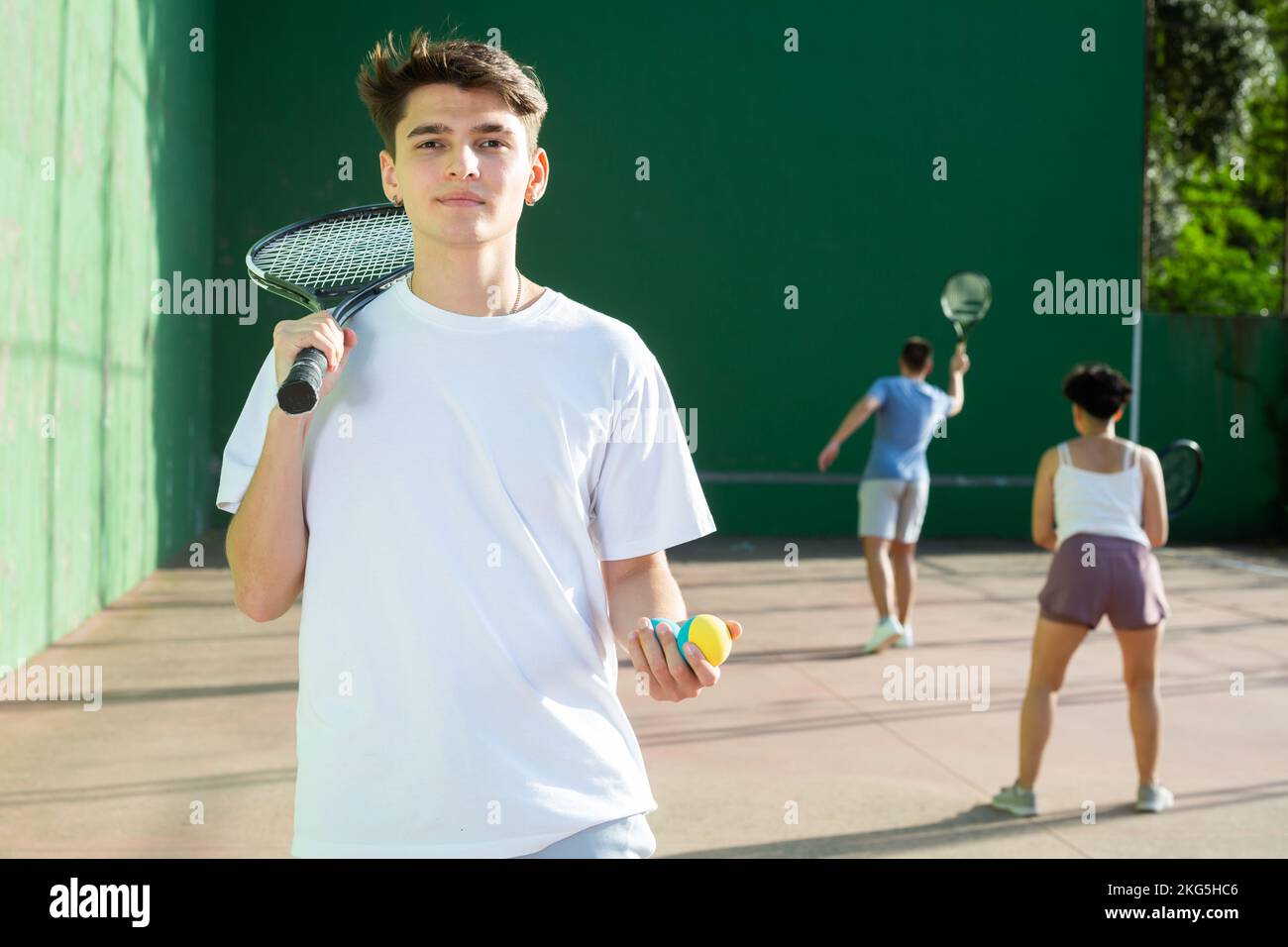 Porträt eines kaukasischen Jungen, der auf dem Frontplatz steht und Schläger und Ball hält Stockfoto