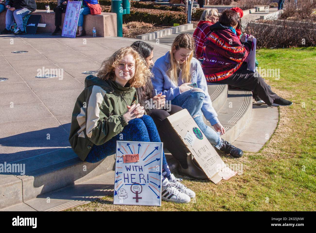 1-18-2020 Tulsa USA Junge Frauen sitzen im frauenmarsch mit Schildern - ein Mädchen lächelt vor der Kamera - Zeichen - Ich bin bei ihr - Lassen Sie uns sprechen Stockfoto
