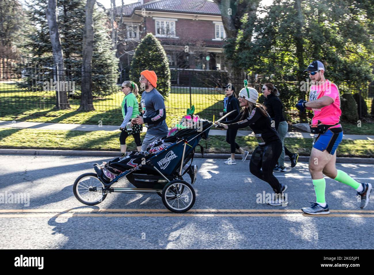 3-16-2019 Tulsa USA - Gruppe kostümierter Läufer bei der St. Patricks Day Parade, die eine behinderte Person drängen, damit sie das Erlebnis mit dem verschwommenen Haus genießen kann Stockfoto