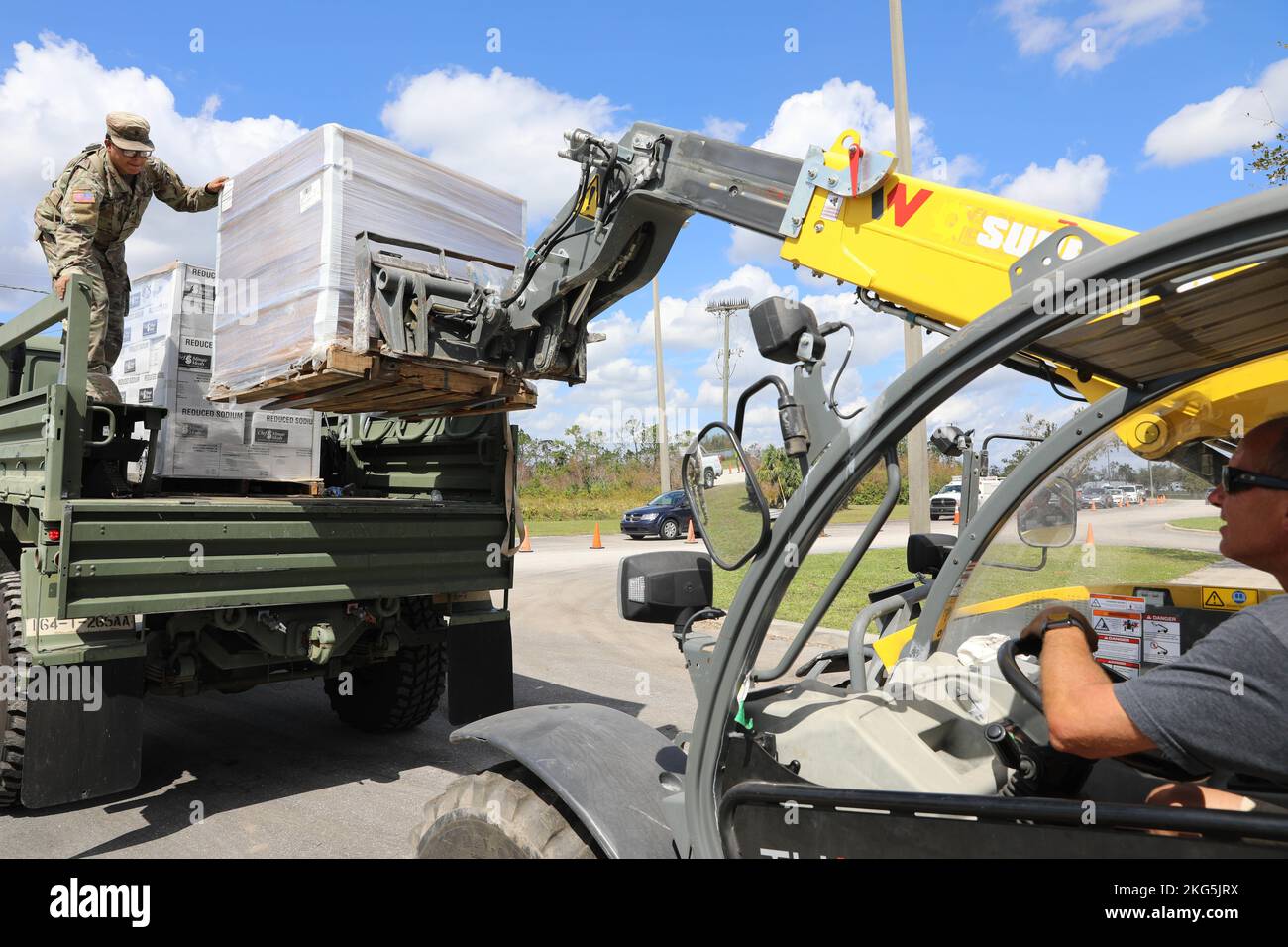 Soldaten der 1-265. Air Defense Artillery (ADA) arbeiten mit Zivilisten zusammen, um ein leichtes Medium Tactical Vehicle (LMTV) voller Nahrung, Wasser und Planen für den mobilen Vertrieb in Englewood, Florida, zu verpacken. 5. Oktober 2022. Als Reaktion auf die Naturkatastrophe wurden mehr als 6.000 Dienstmitglieder aktiviert, und es wurden sowohl militärische als auch zivile Unterstützung von Orten außerhalb des Bundesstaates unterstützt. Stockfoto