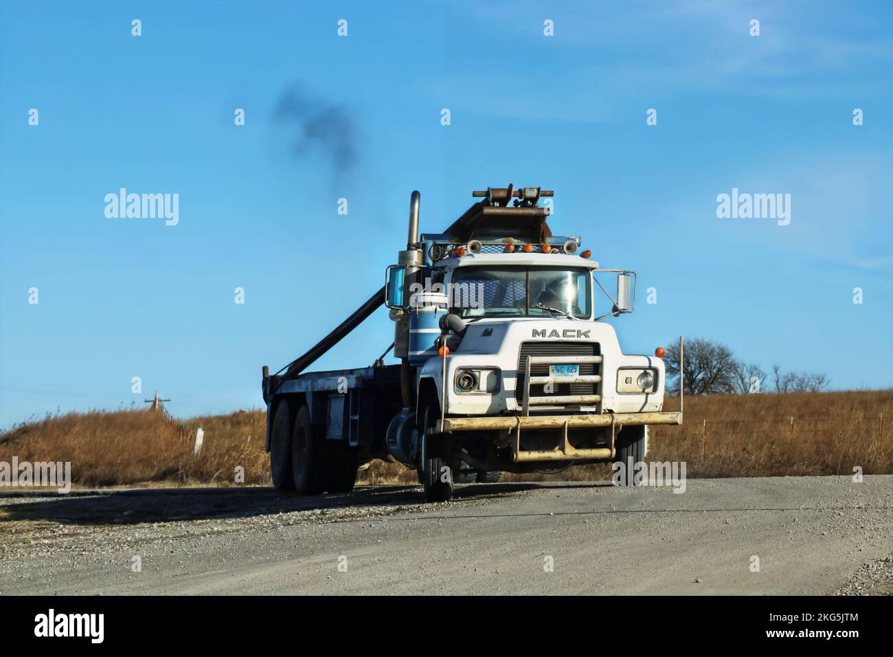 2017 11 30 Oklahoma USA - der alte, funktionierende Mackkarren mit Weide und ausgebrochenem Scheinwerfer fährt auf einer Schotterstraße mit Winterweide in der Ferne eine Kurve Stockfoto