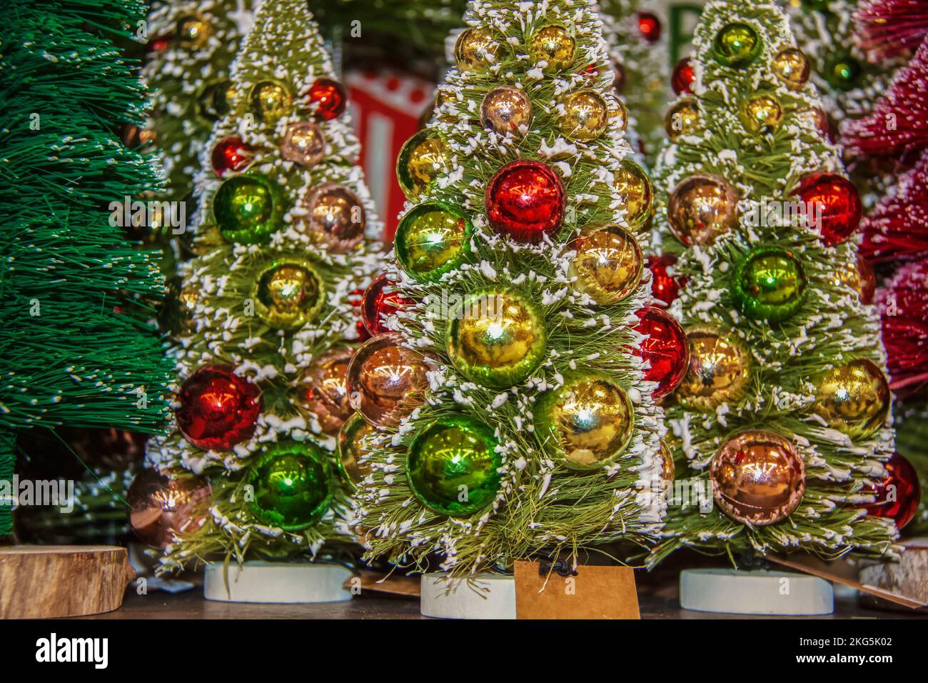 Hintergrund von Miniatur beflockte Weihnachtsbäume mit glänzenden runden Ornamenten - selektiver Fokus auf den Vordergrund Stockfoto
