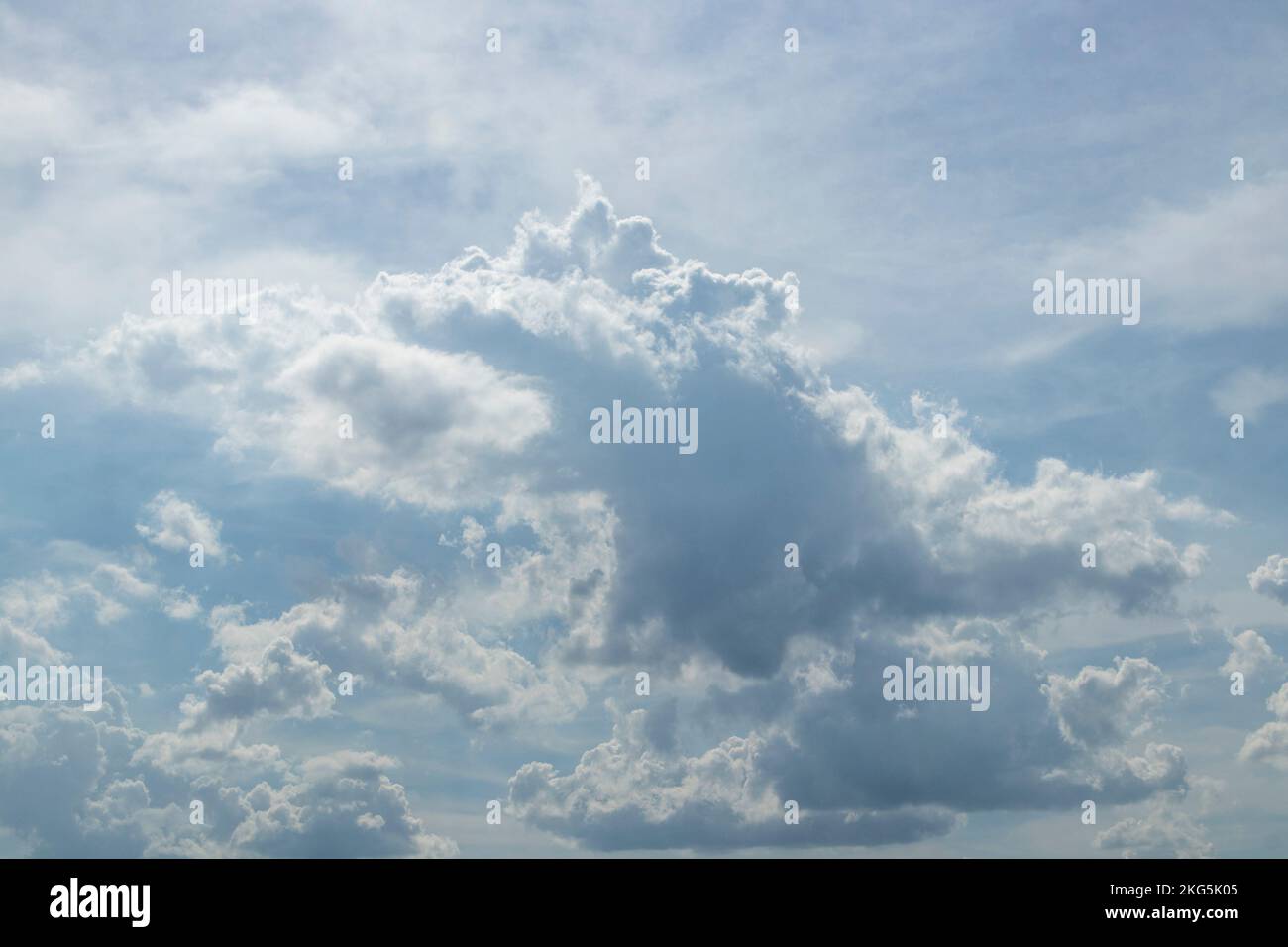 Blauer Himmel mit flauschigen Wolken, die wie Dinosaurier oder Feuer speiender Drache aussehen Stockfoto