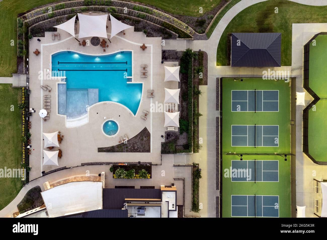 Luftblick auf große Tennisplätze, Swimmingpool im gemeinschaftlichen Erholungszentrum mit Villen mit Loungebereichen im Sommer im Freien. Stockfoto