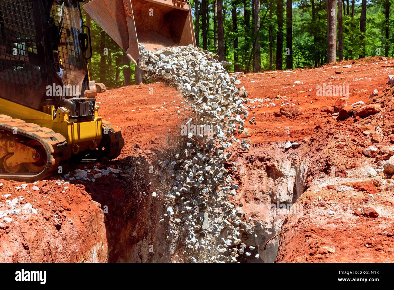 Bobcat Mini Loader schläft mit zerdrücktem Stein in die Entwässerungsgrube ein Stockfoto
