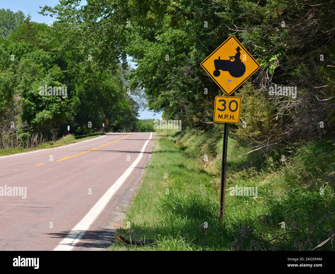 Ein Schild mit der Aufschrift „Slow down for Tractors“ neben einer Landstraße Stockfoto