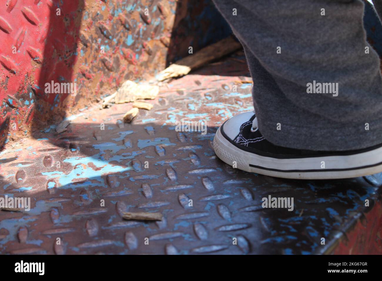 Nahaufnahme eines Kinderschuhs, der Converse All-Stars trägt und im Mittleren Westen Amerikas die Leiter zu einer Spielplatzrutsche hochklettert. Stockfoto