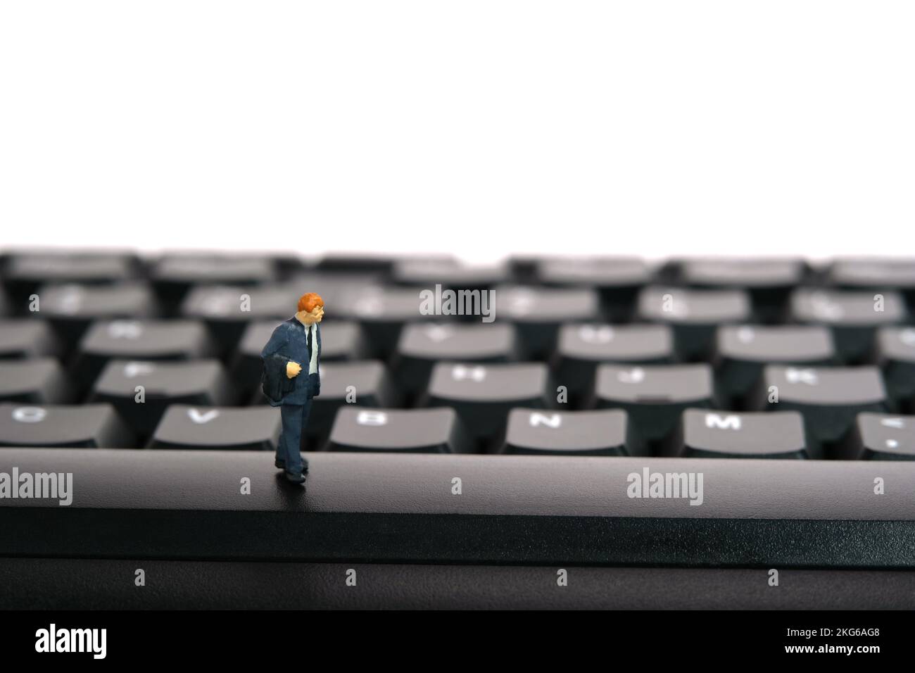 Miniatur-Menschen-Spielzeug-Figuren-Fotografie. Ich habe das Überstundenkonzept satt. Ein Geschäftsmann, der über der Tastatur steht. Bildfoto Stockfoto