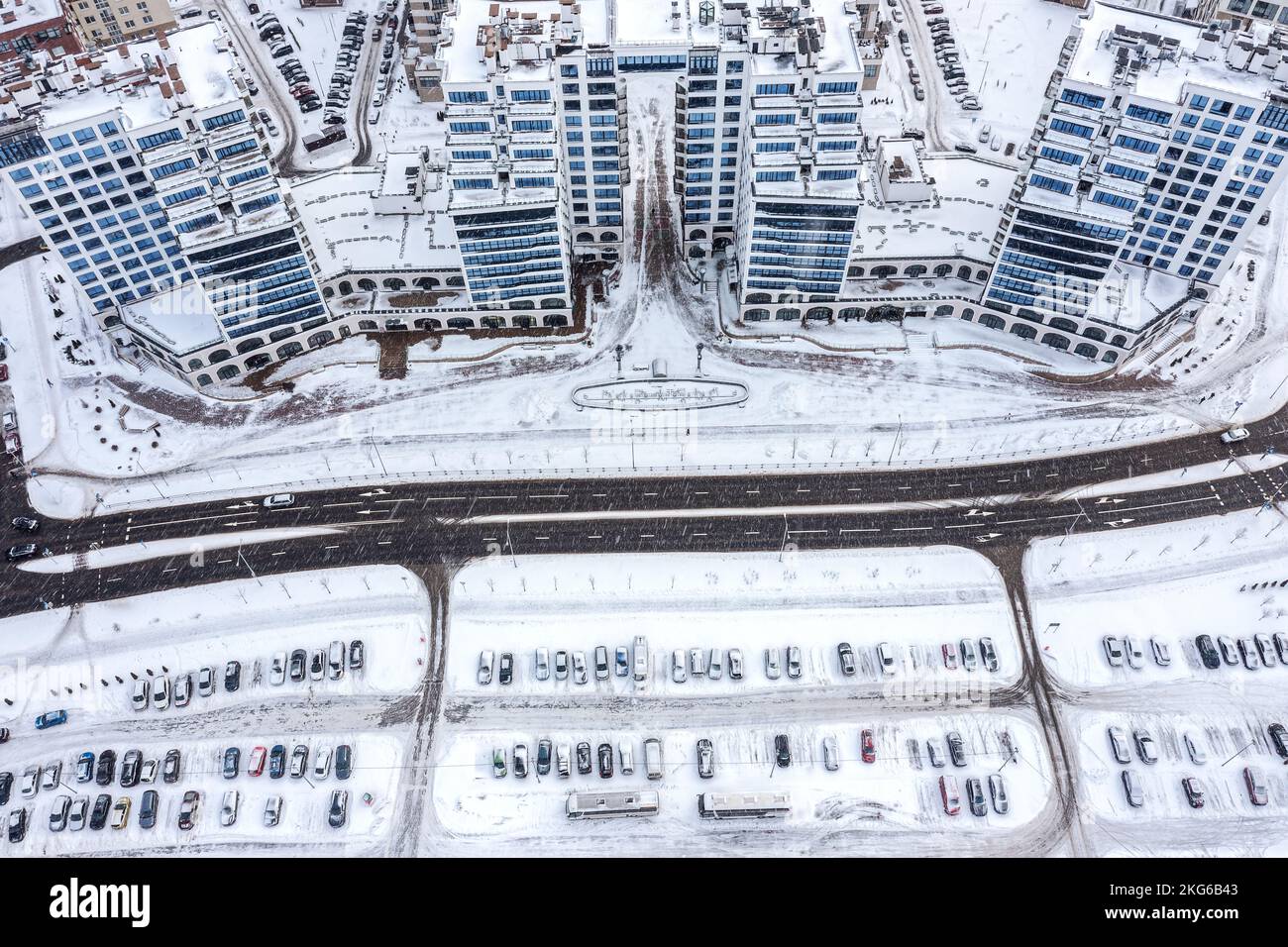 Wohnviertel und Parkplatz mit Autos im Winter bei starkem Schneefall. Luftaufnahme. Stockfoto