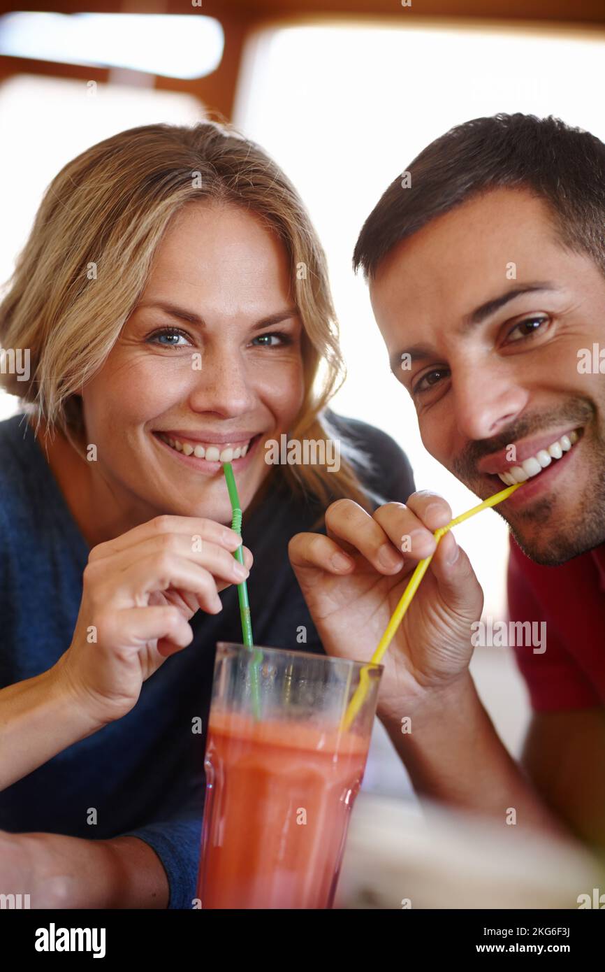 Altmodische Romantik. Porträt eines glücklichen jungen Paares, das einen Milchshake teilt. Stockfoto