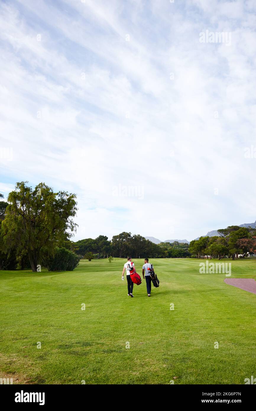 Raus in die Natur. Rückansicht von zwei Freunden auf dem Golfplatz zusammen. Stockfoto