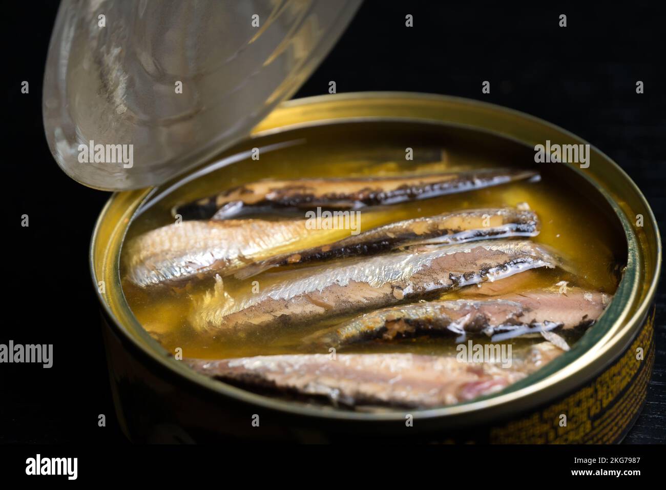 Nahaufnahme einer offenen Sprottendose in Öl auf schwarzem Hintergrund Stockfoto