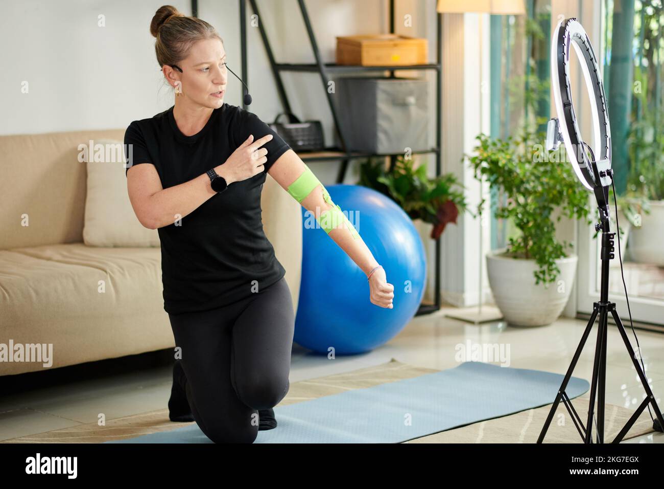 Fitnesstrainer filmt sich selbst mit elastischem Therapiestreifen am Arm Stockfoto