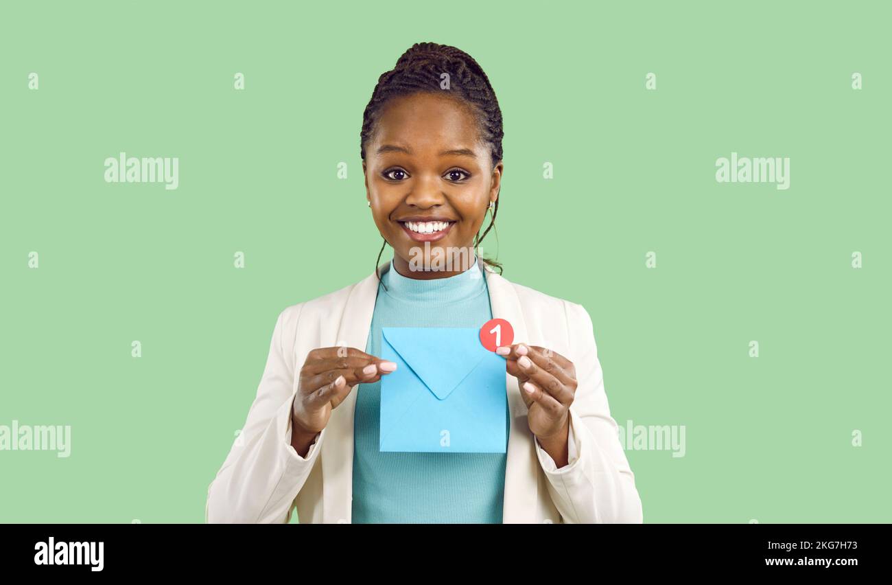 Eine lächelnde schwarze Frau hält einen Umschlag mit ungelesener Benachrichtigung Stockfoto