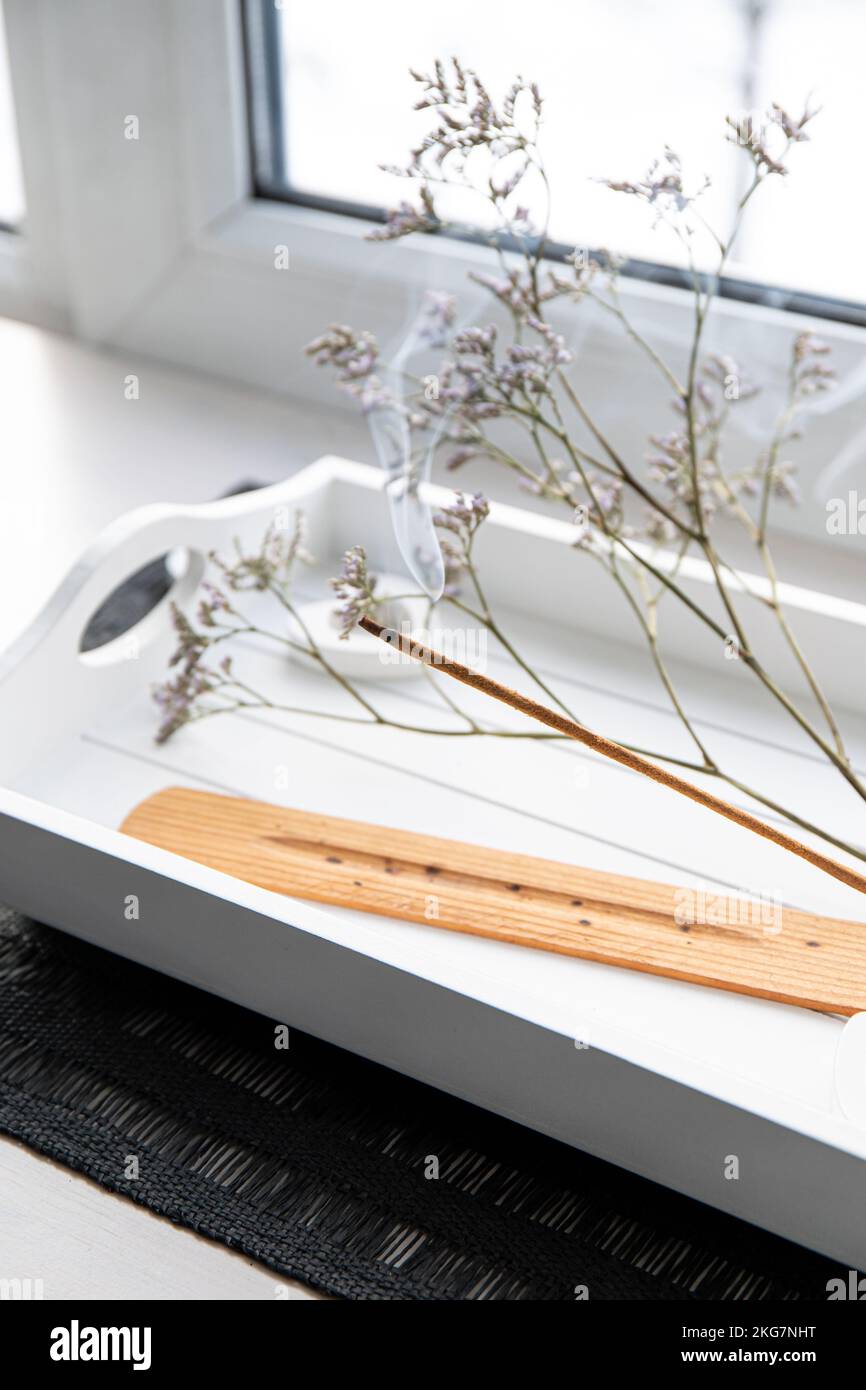 Duftdesign. Heim Fensterbank mit Weihrauch Kerze, die auf einem weißen, minimalistischen Tablett brennt, schaffen gute Stimmung mit gutem angenehmen Duft. Stockfoto