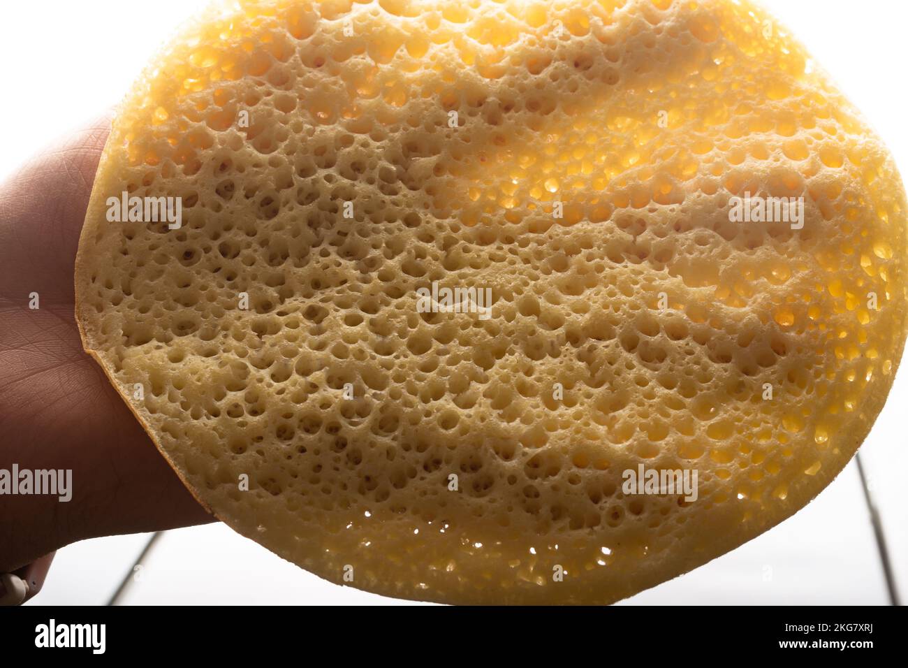 Eine Hand nimmt einen marokkanischen Pfannkuchen, Baghrir typisch marokkanisches Frühstücks-Dessert Stockfoto