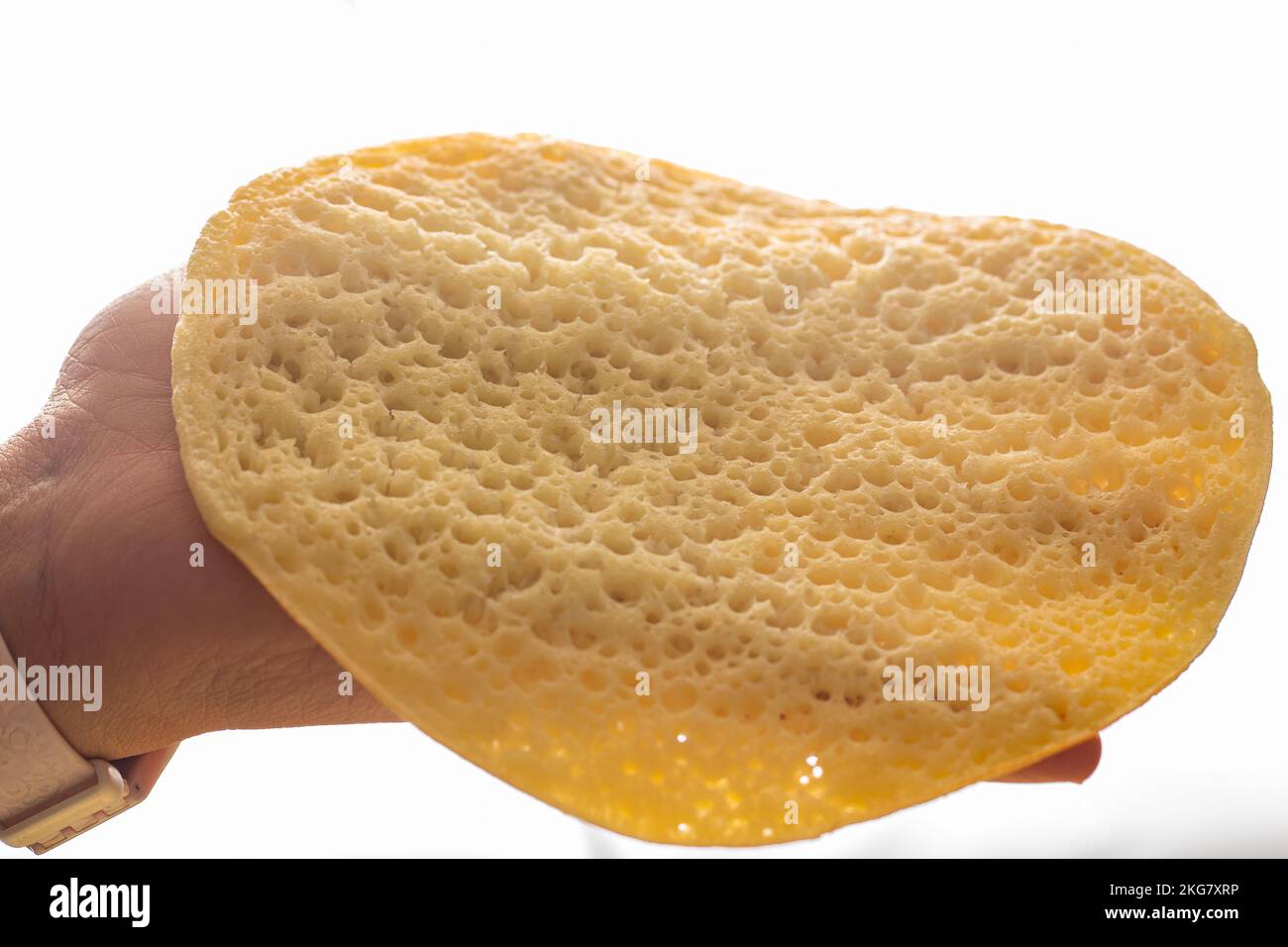 Eine Hand nimmt einen marokkanischen Pfannkuchen, Baghrir typisch marokkanisches Frühstücks-Dessert Stockfoto