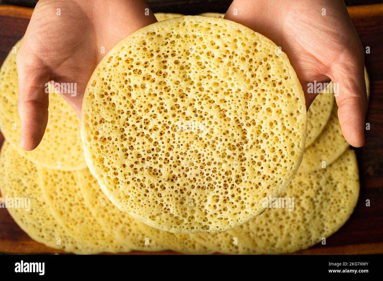 Eine Hand nimmt einen marokkanischen Pfannkuchen, Baghrir typisch marokkanisches Frühstücks-Dessert Stockfoto