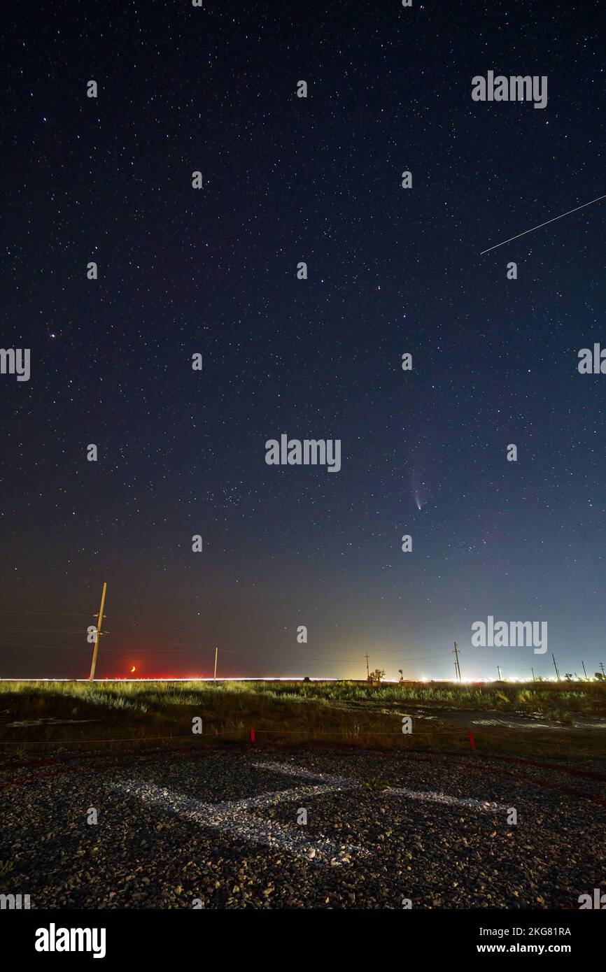 Echtes Sternenfoto von Neowise Comet C2020 F3 NEOWISE bei Mondaufgang. Neumond Halbmond am Horizont über dem Hubschrauberlandeplatz oder Heliport. Henychensk, Ukraine an Stockfoto
