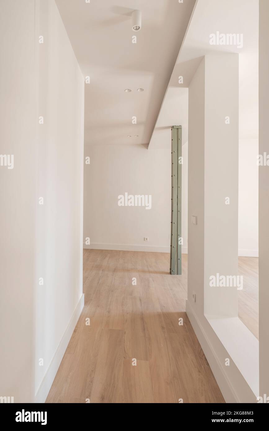 Eingangshalle mit großer, offener Fläche, alten Metallsäulen und minimalistischem Design mit glatten Oberflächen und Holzfußboden aus Steinzeug Stockfoto