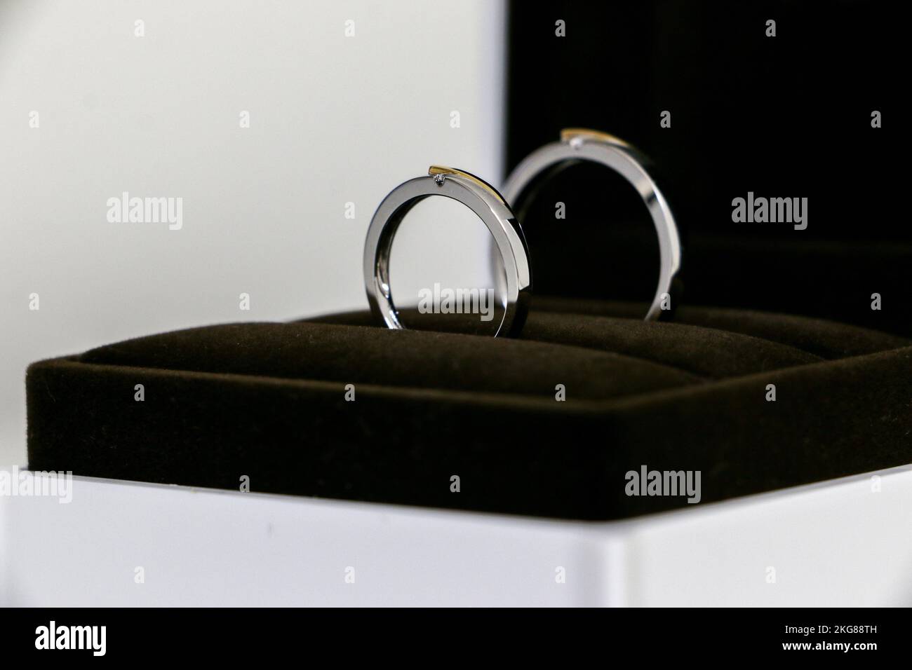 Nahaufnahme eines Paares von Eheringen, die in einer offenen Ringbox funkeln, Symbol für Romantik, Liebe, Ehe. Stockfoto