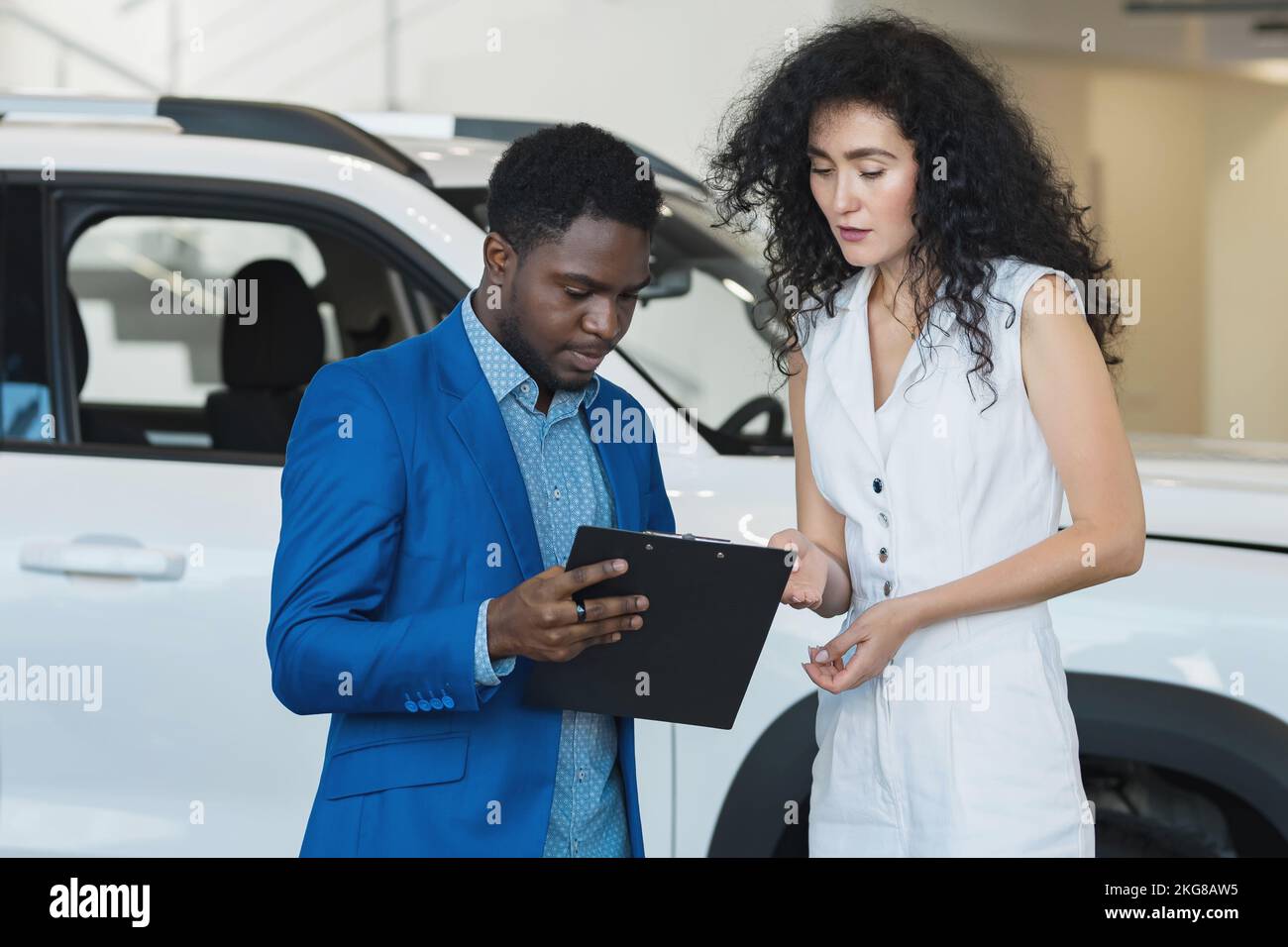 Afroamerikanischer Verkäufer präsentiert dem Kunden das Auto Stockfoto
