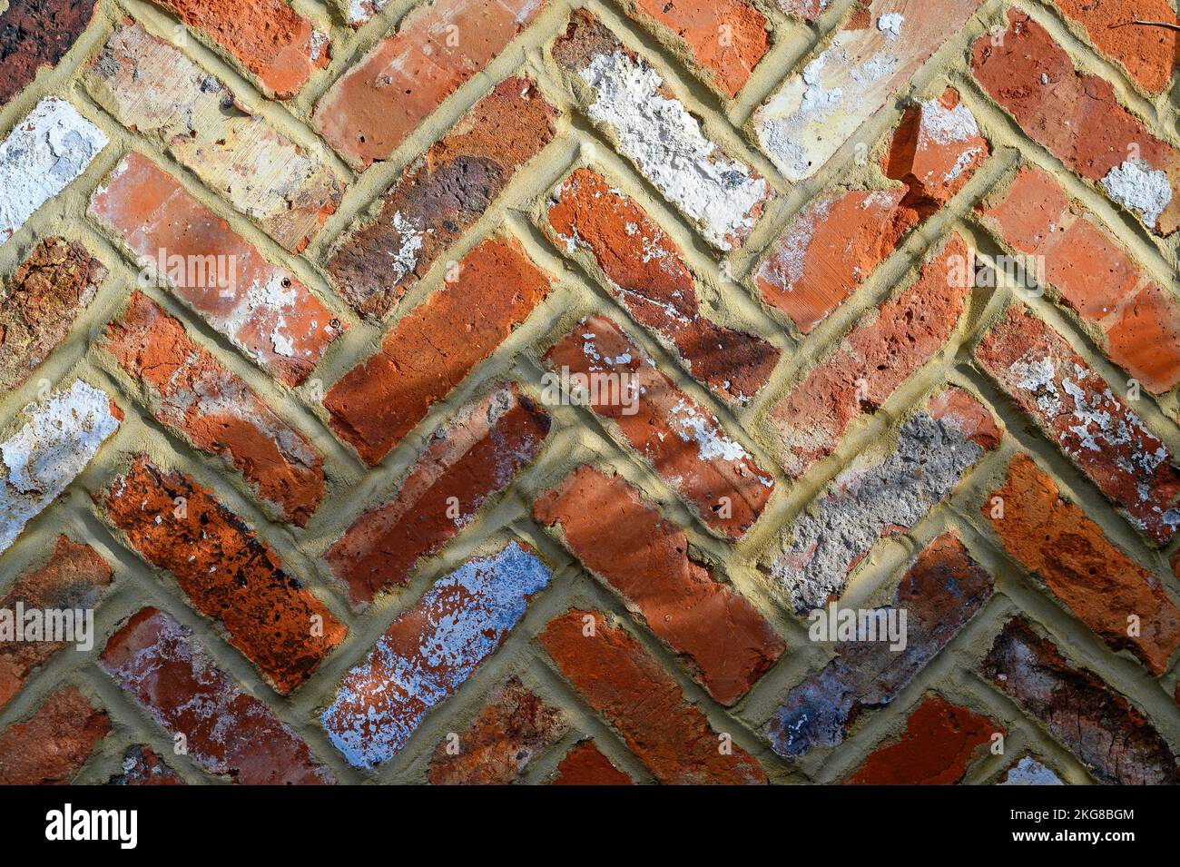 Rote Backsteinwand mit Fischgrätmuster. Diese Ziegelwand hat ein Interessantes Muster, verschiedene Farben und eine raue Textur. Backsteinmauer in Beckenham, Großbritannien Stockfoto