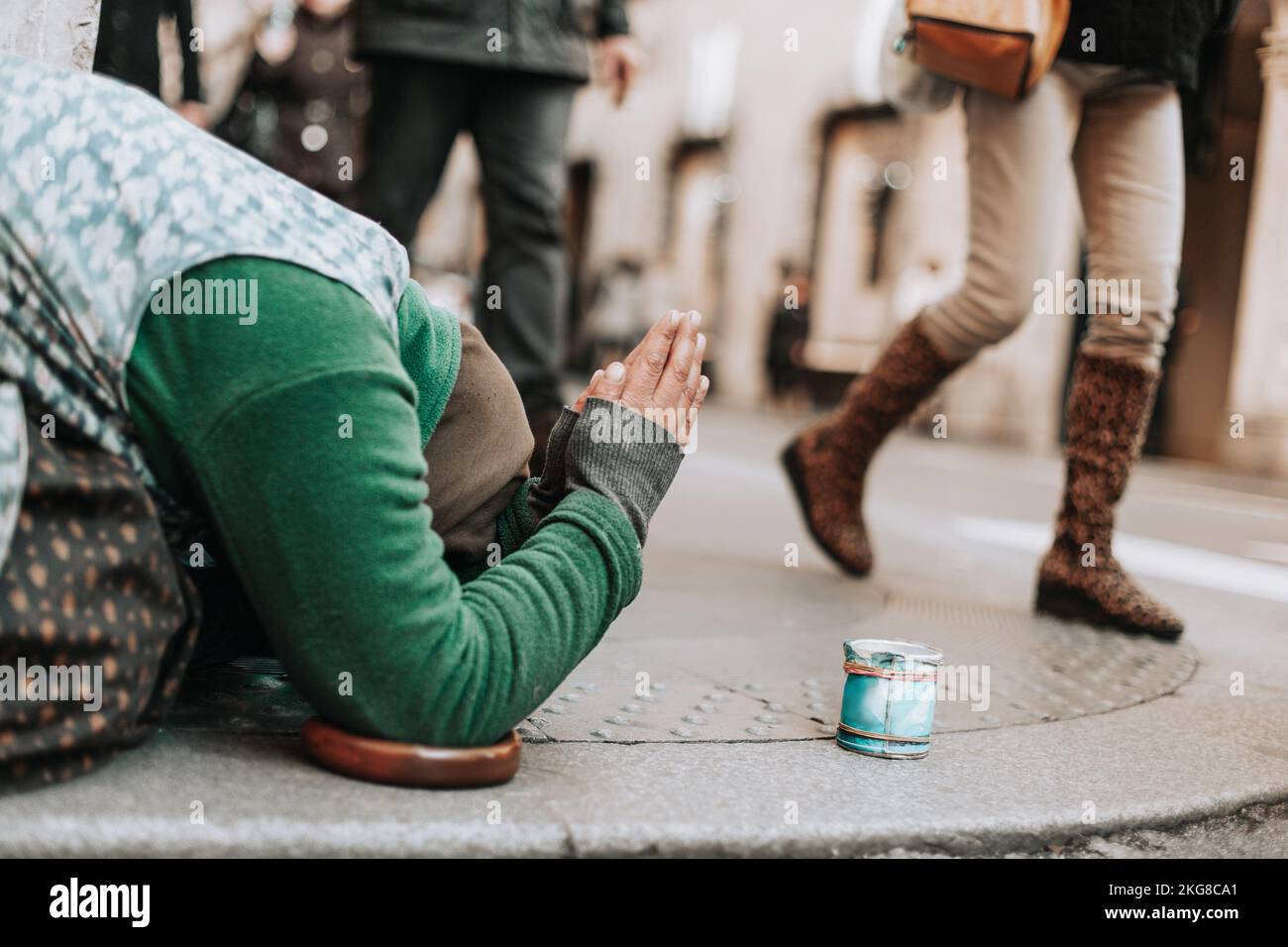 Eine Frau auf den Knien bettelt um Almosen auf einer Straße Stockfoto