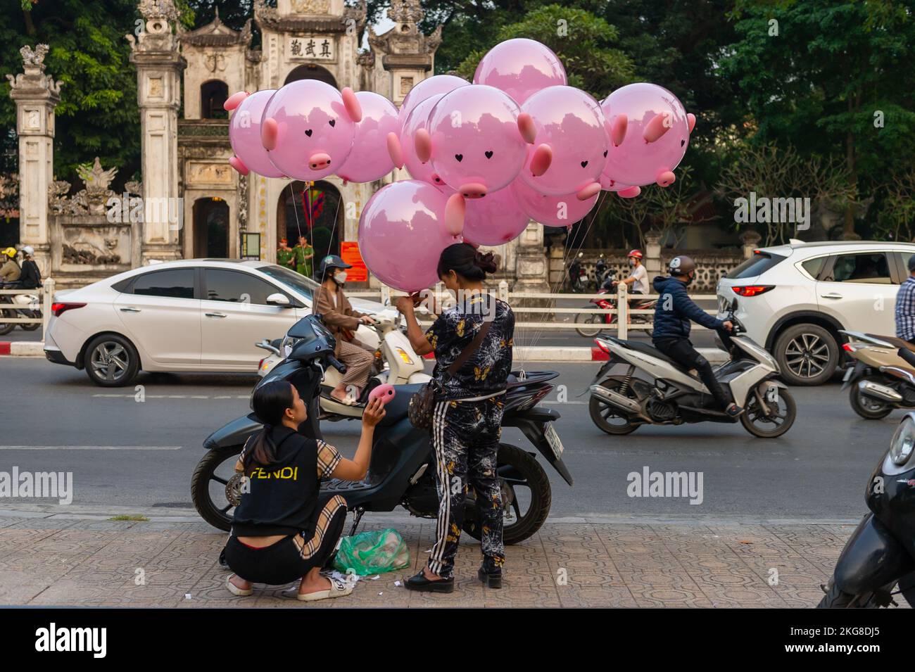 Verkauf rosa Schweineballons auf der Straße vor dem Quan Thanh Tempel während der Rush Hour, Hanoi, Vietnam Stockfoto