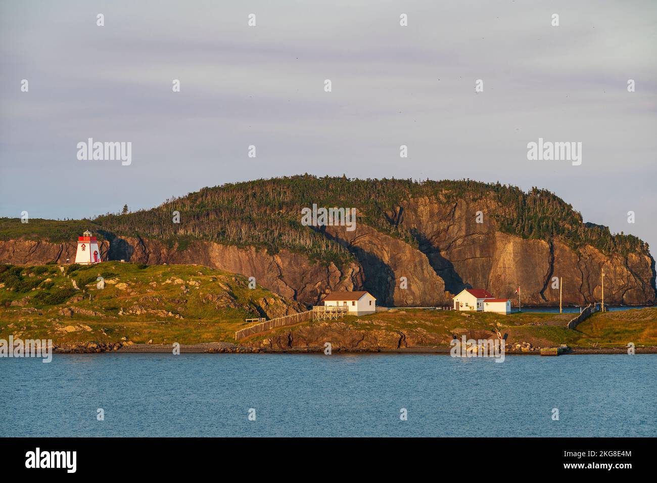Kanada, Labrador, Neufundland, Trinity, Meeresküste mit entferntem Leuchtturm Fort Point bei Sonnenuntergang Stockfoto