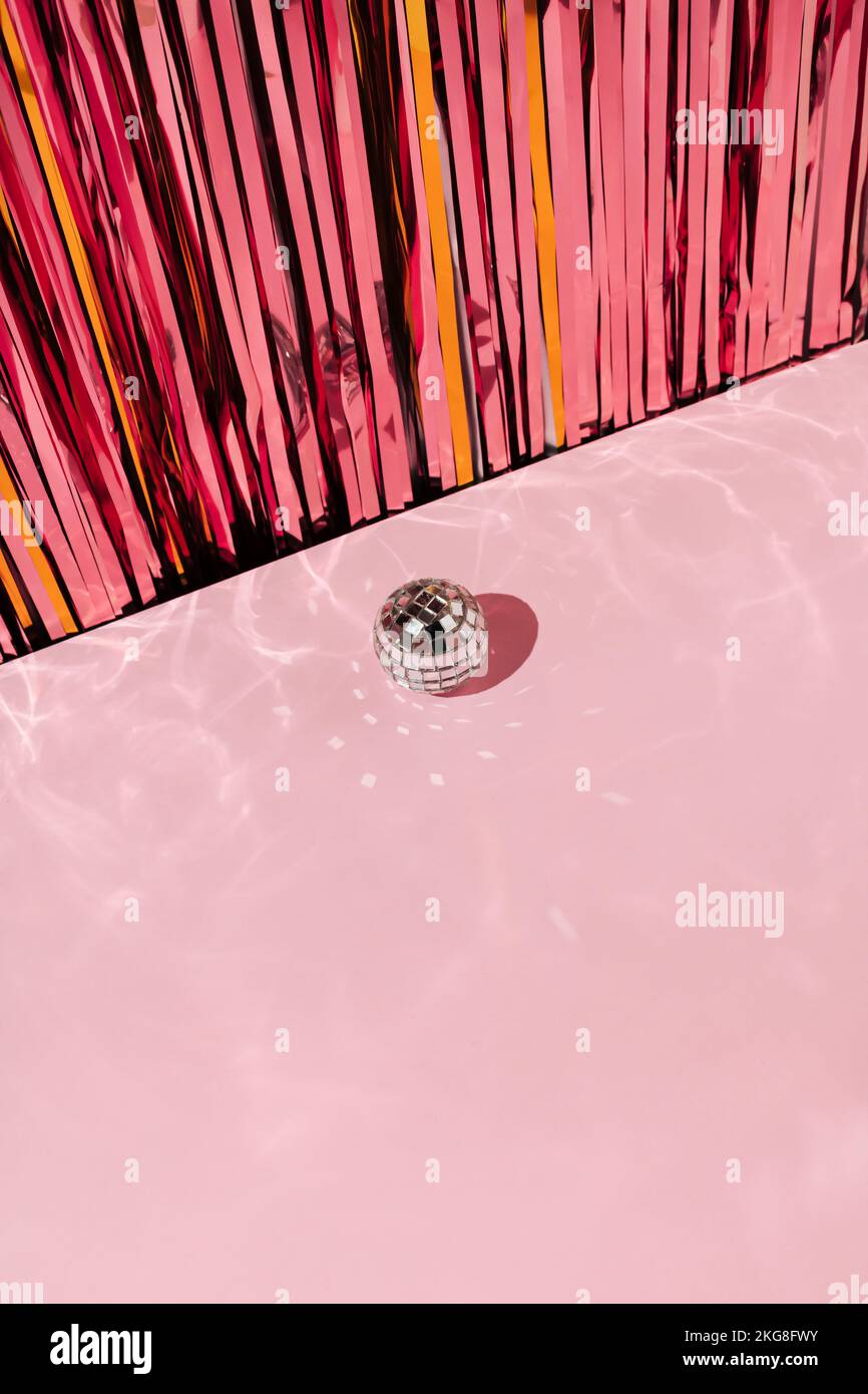 Glänzender Discoball mit pinkfarbenen und goldenen Weihnachtstinketten. Neujahrsgrüßungskonzept. Stockfoto