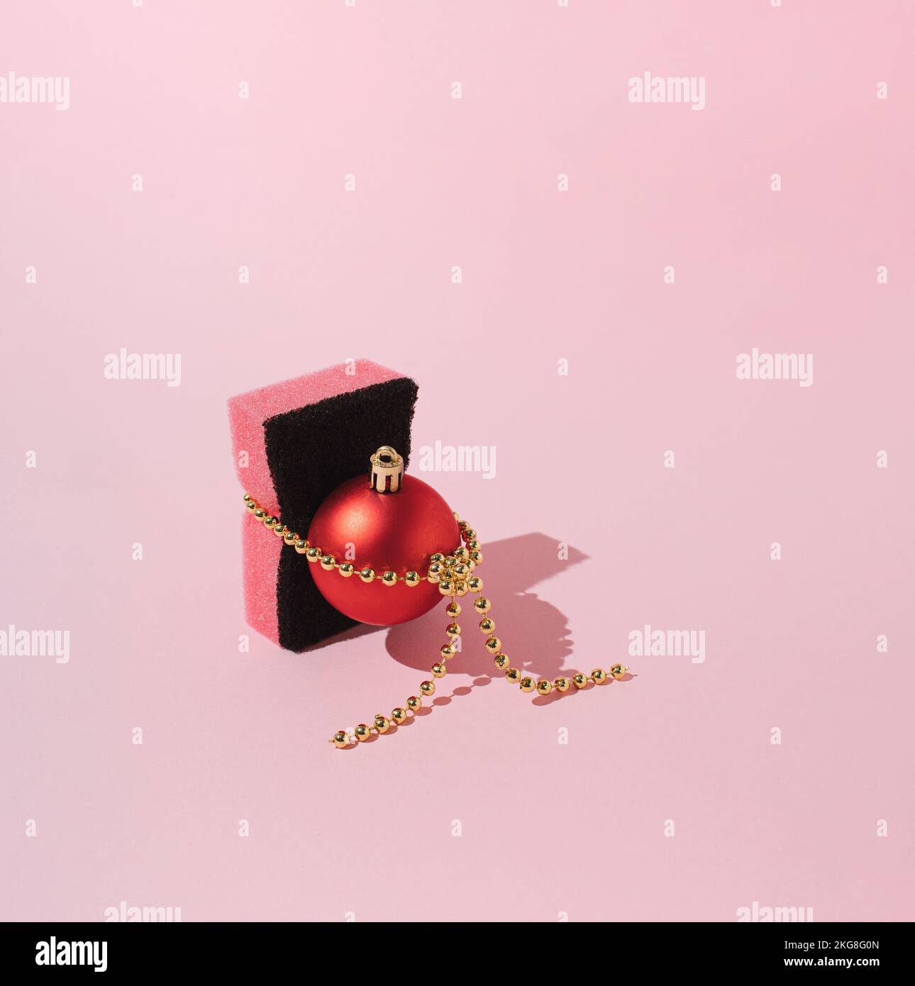 Weihnachtsschmuck mit einem Küchenschwamm auf pinkfarbenem Hintergrund. Minimales Neujahrskonzept. Stockfoto