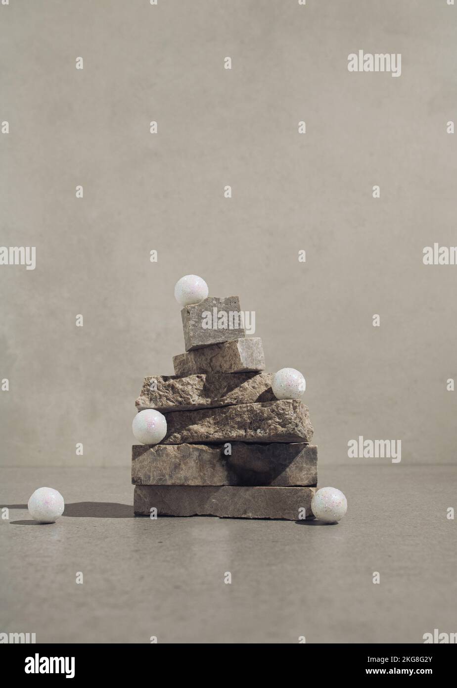 Weiße dekorative Weihnachtskugeln auf einem Weihnachtsbaum aus Naturstein. Minimales Begrüßungskonzept. Stockfoto