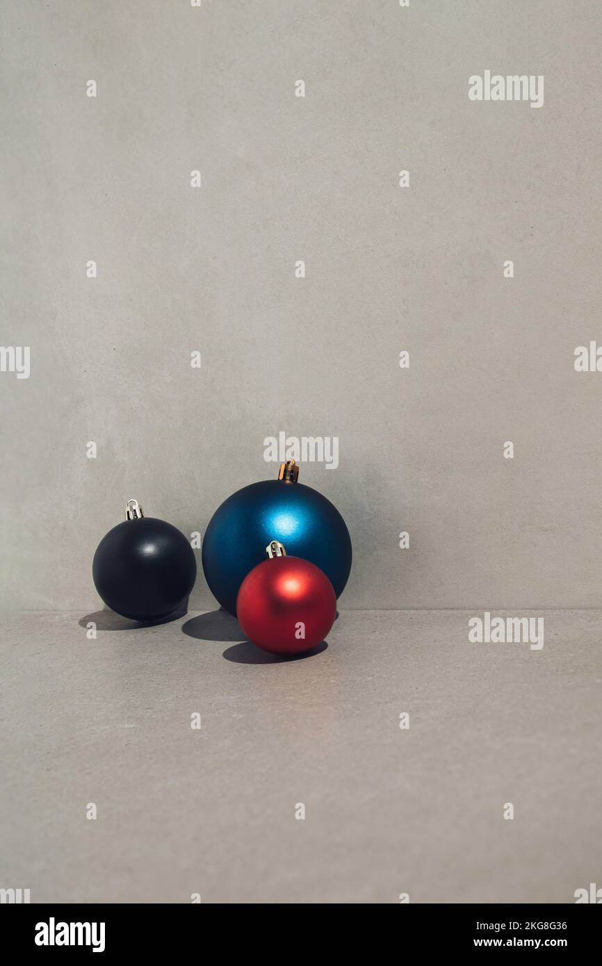 Drei Weihnachtskugeln auf grauem Steinhintergrund. Neujahrskonzept. Stockfoto