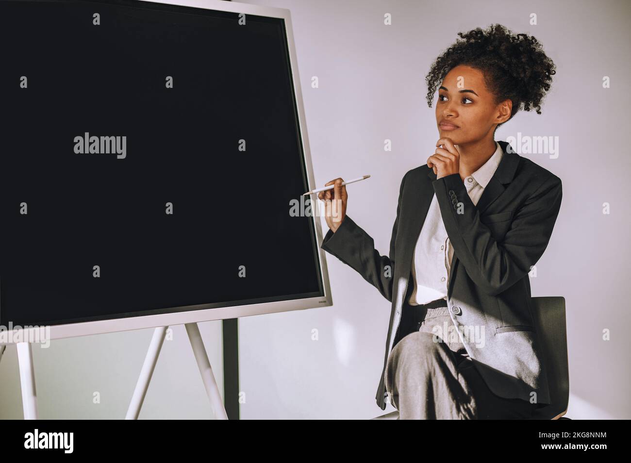 Attraktive Geschäftsfrau, die während der Firmenpräsentation nachdenkt Stockfoto