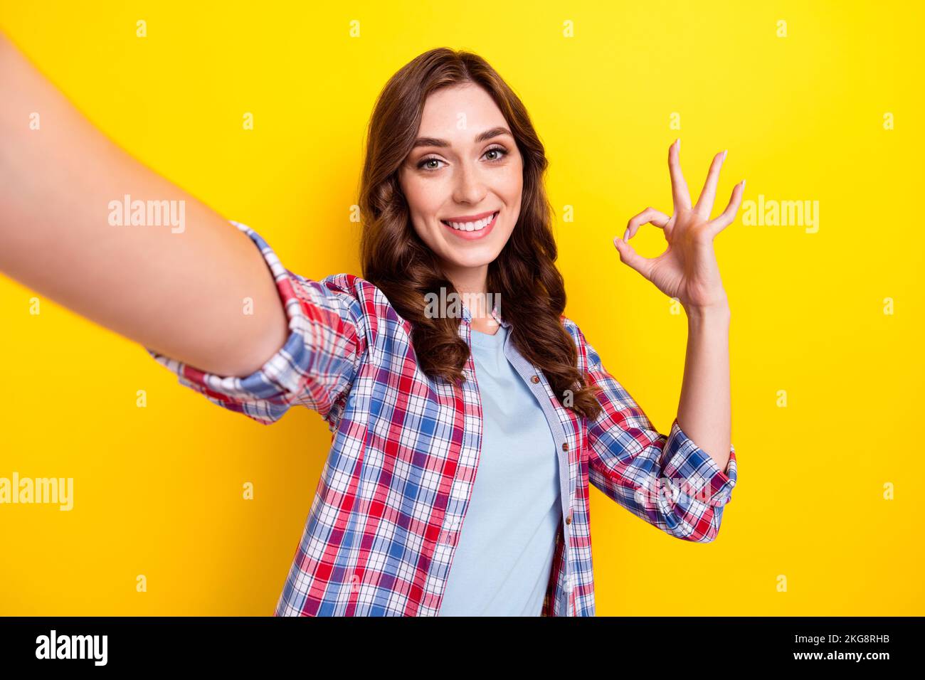 Selfie-Porträtfoto einer jungen süßen Frau mit OKY-Zeichen alles cool Beliebte Blogger empfehlen neue Kamera isoliert auf gelbem Hintergrund Stockfoto