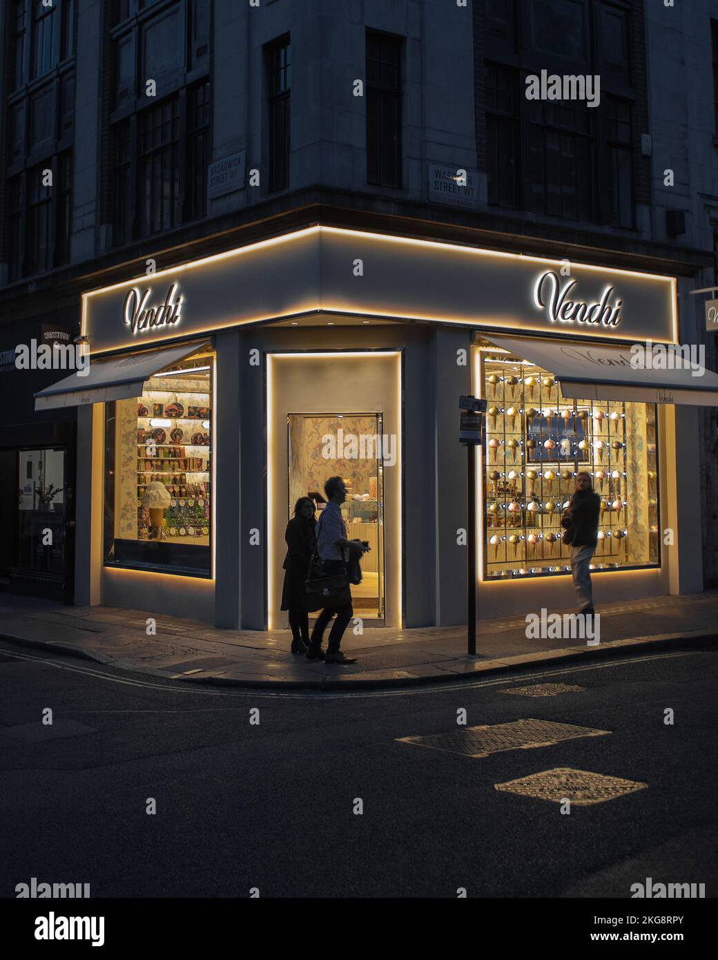 3 Leute, die bei Nacht an Venchi, Wardour Street, London vorbeilaufen. Stockfoto