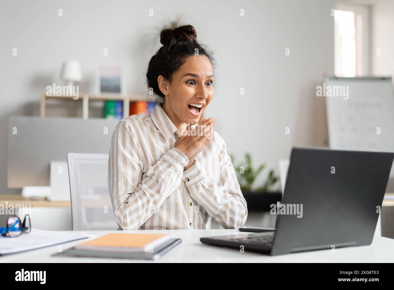 Beförderung, Gewinnkonzept. Aufgeregte Geschäftsfrau, die großartige Neuigkeiten und Glück feiert und sich vor Freude auf den Laptop-Bildschirm blickt Stockfoto