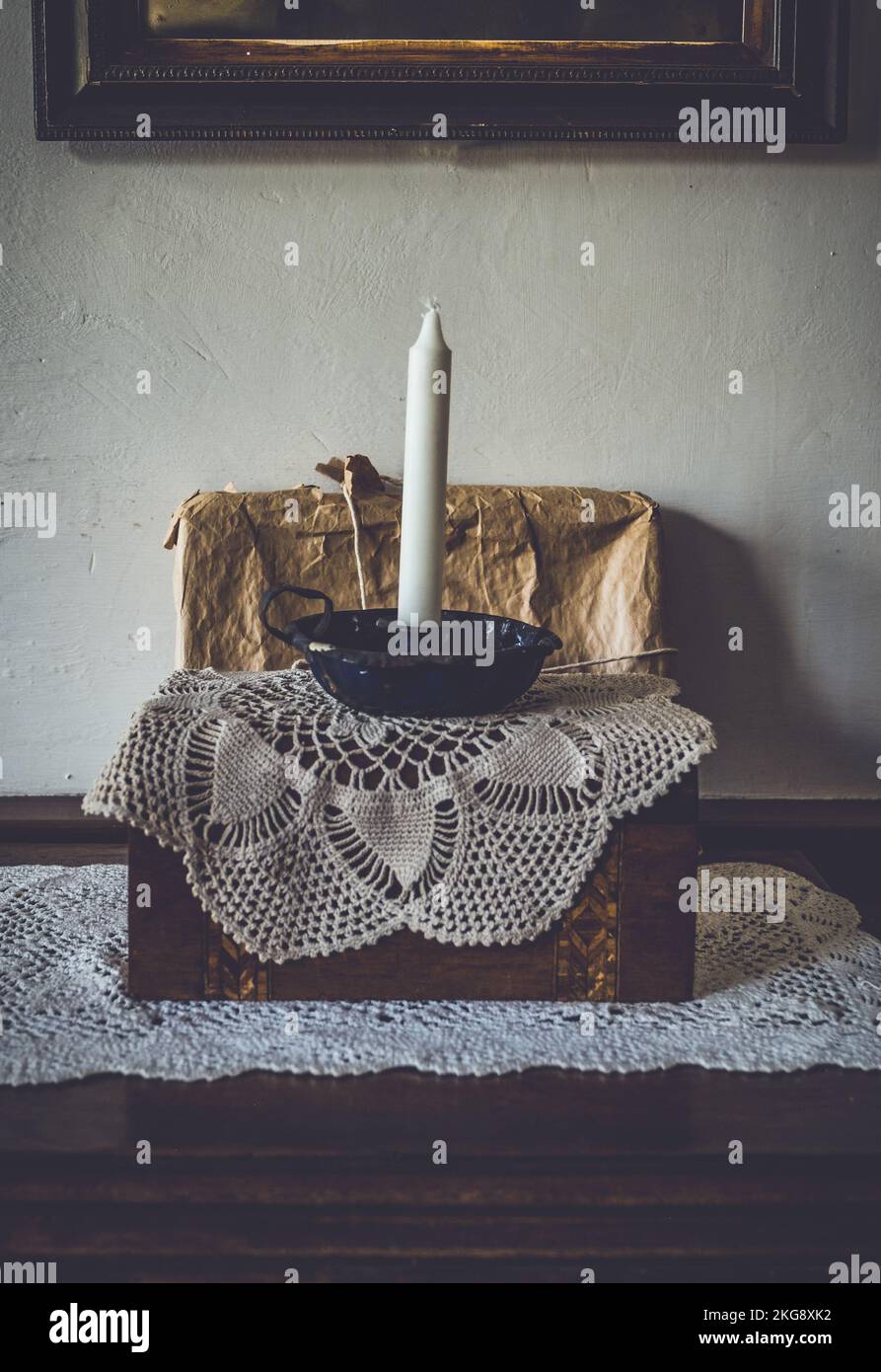 Eine unbeleuchtete Kerze in einem alten Metallhalter auf einer Kommode. Stockfoto