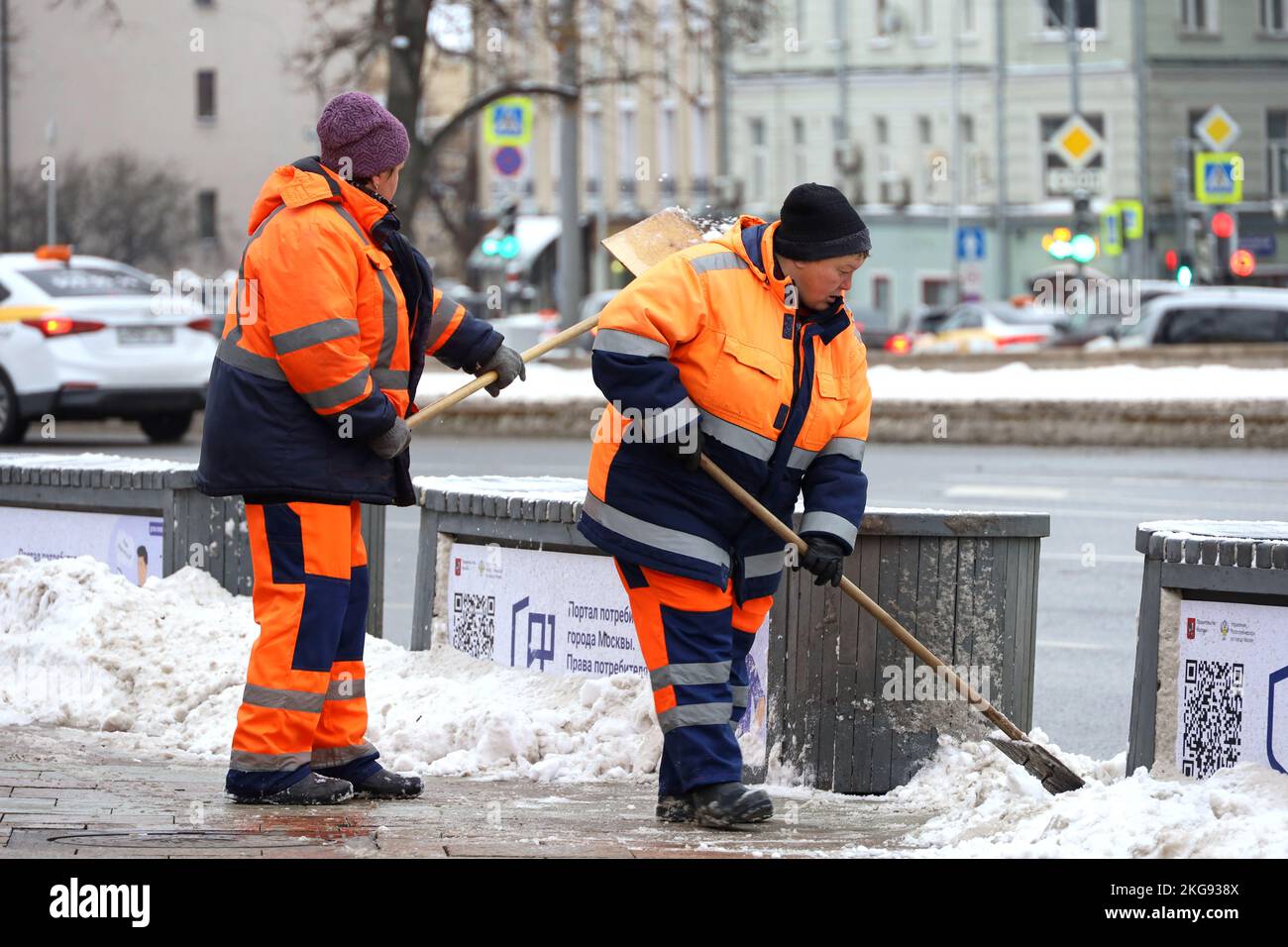 Zwei Arbeiterinnen säubern Schnee mit Schaufeln, Schneeräumen in der Stadt nach Schneefall. Winterwetter, Straßenreinigung in Moskau Stockfoto