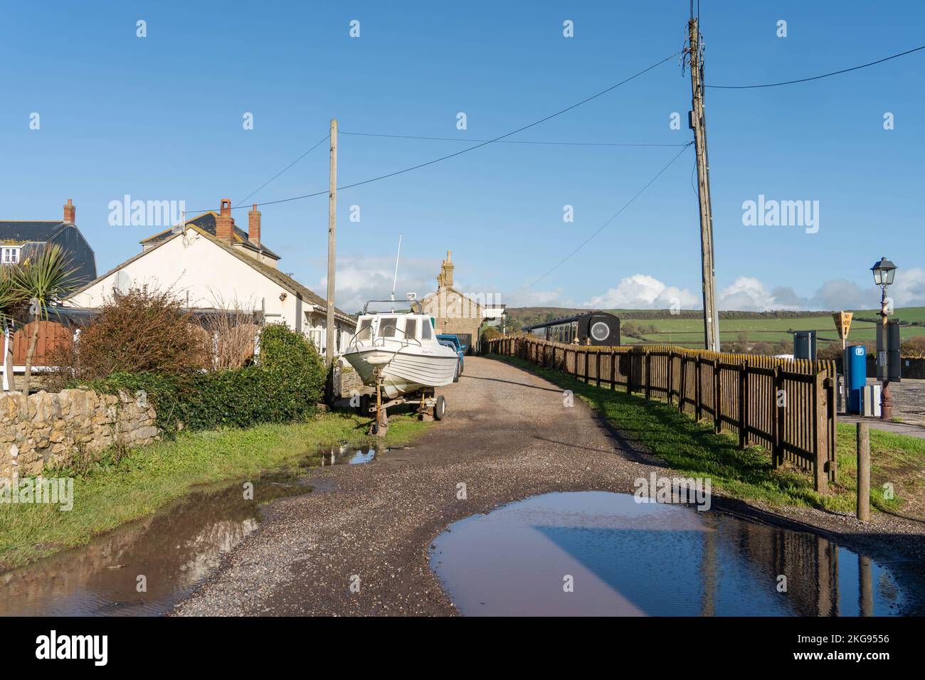 Blick auf die Küstensiedlung von West Bay, Dorset, Großbritannien - ein Boot im Vordergrund und The Station Kitchen - ein Restaurant in einem ehemaligen Eisenbahnwaggon. Stockfoto